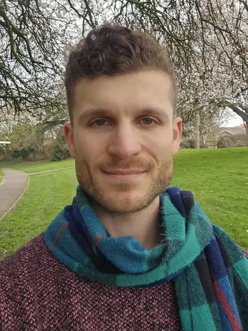 Arian Aseeley outdoors in a park wearing a blue and green scarf